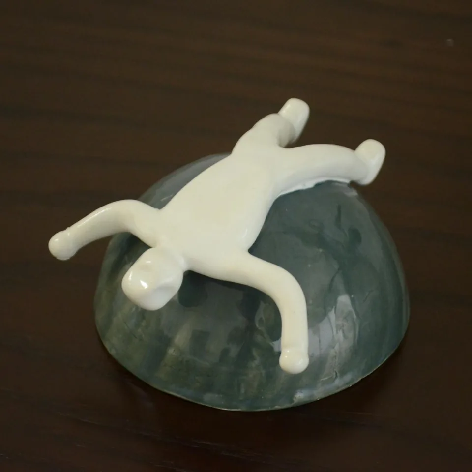 Figura blanca recostada sobre una forma verde.