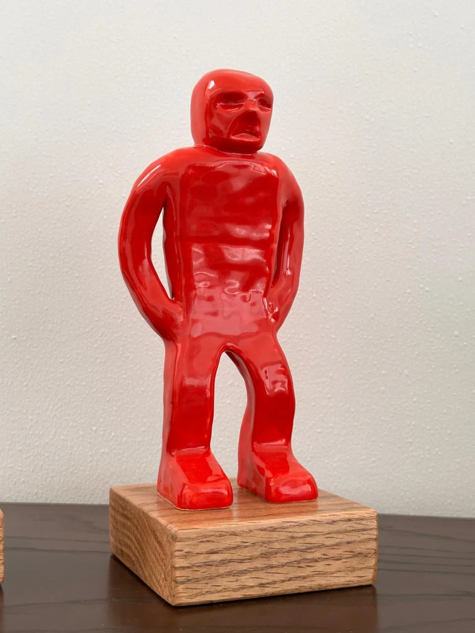 Escultura roja de figura humana sobre una base de madera.