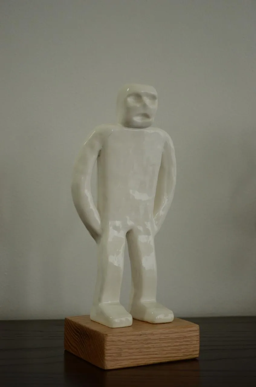 U-Mano 03, figura blanca de pie sobre una base de madera.
